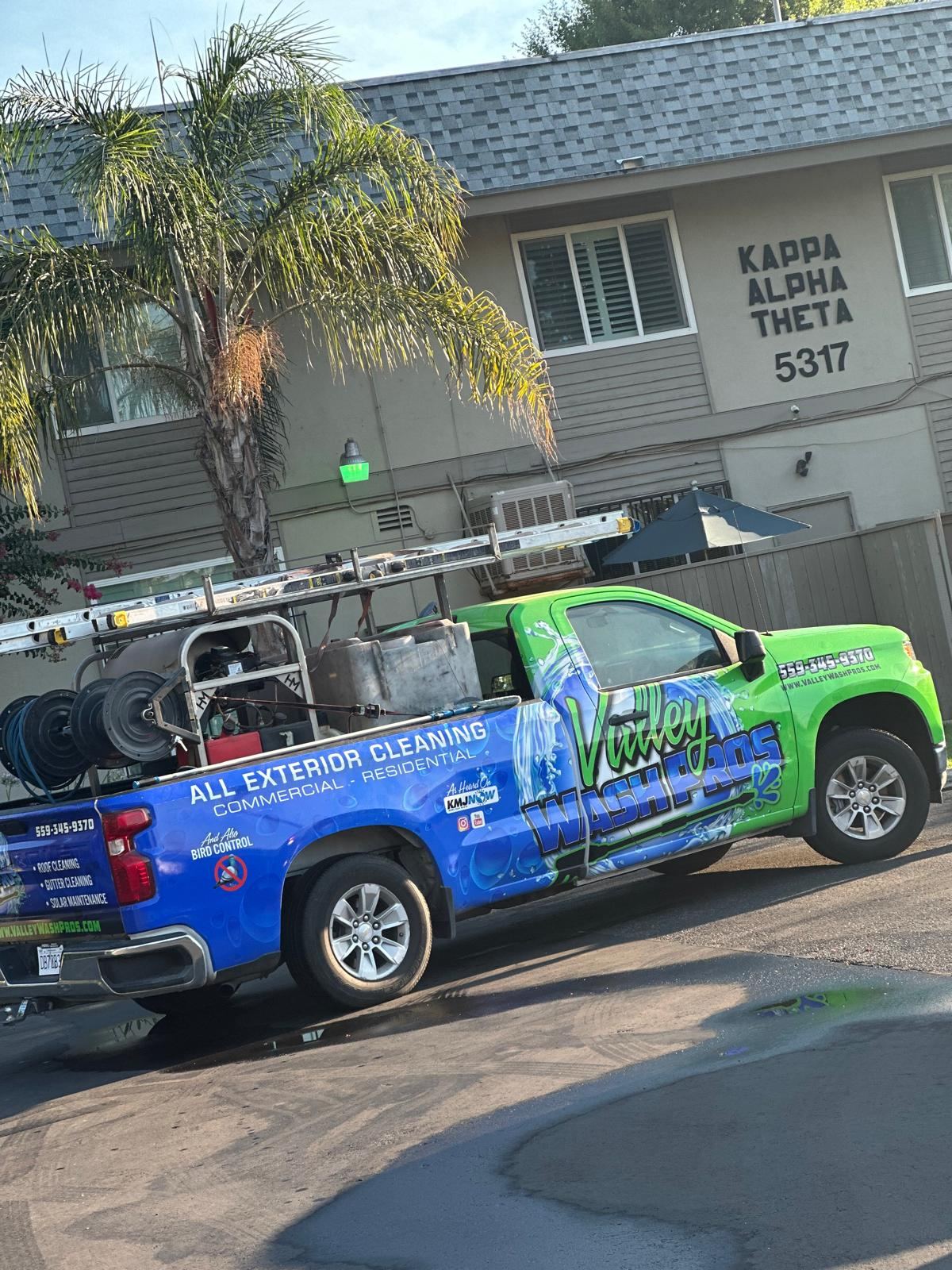 Valley Wash Pros truck set up to wash a multi-unit residential building with a tall stucco facade