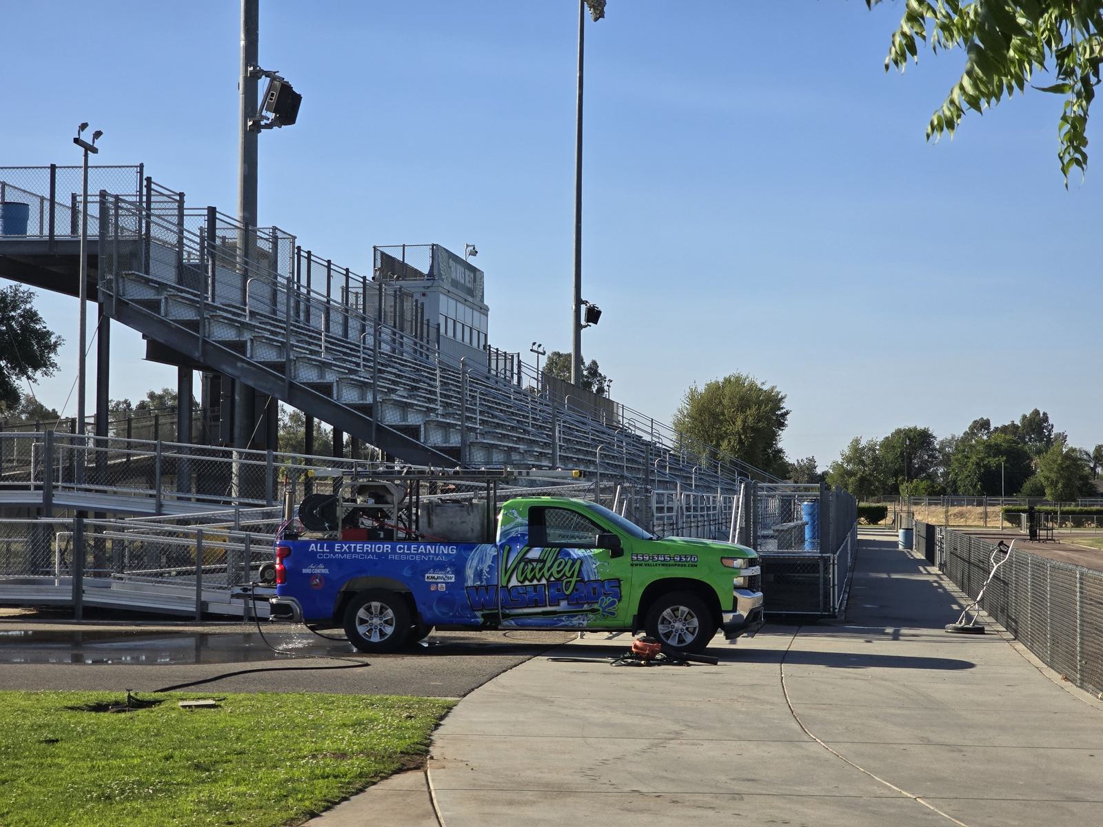 Valley Wash Pros truck pressure washing bleachers and concrete at a school stadium