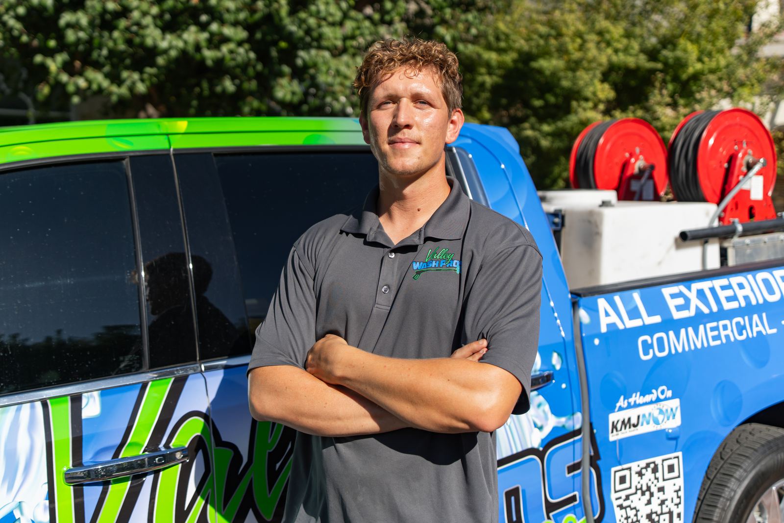 The owner of Valley Wash Pros standing in front of the company's green wrapped service truck