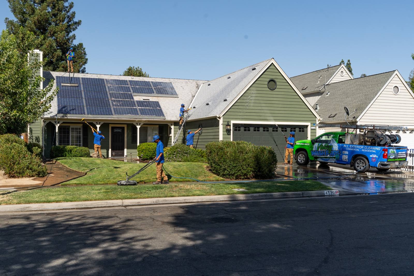 Technician soft washing a home exterior with low-pressure equipment