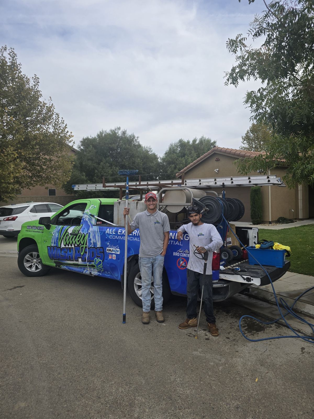 Two uniformed Valley Wash Pros technicians standing beside their service truck