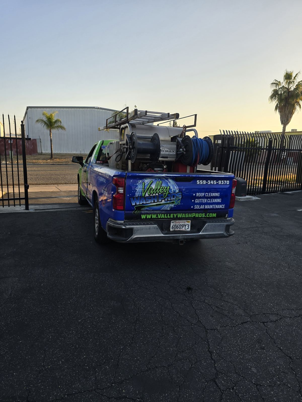 Valley Wash Pros truck loaded with equipment in a commercial parking lot at sunrise