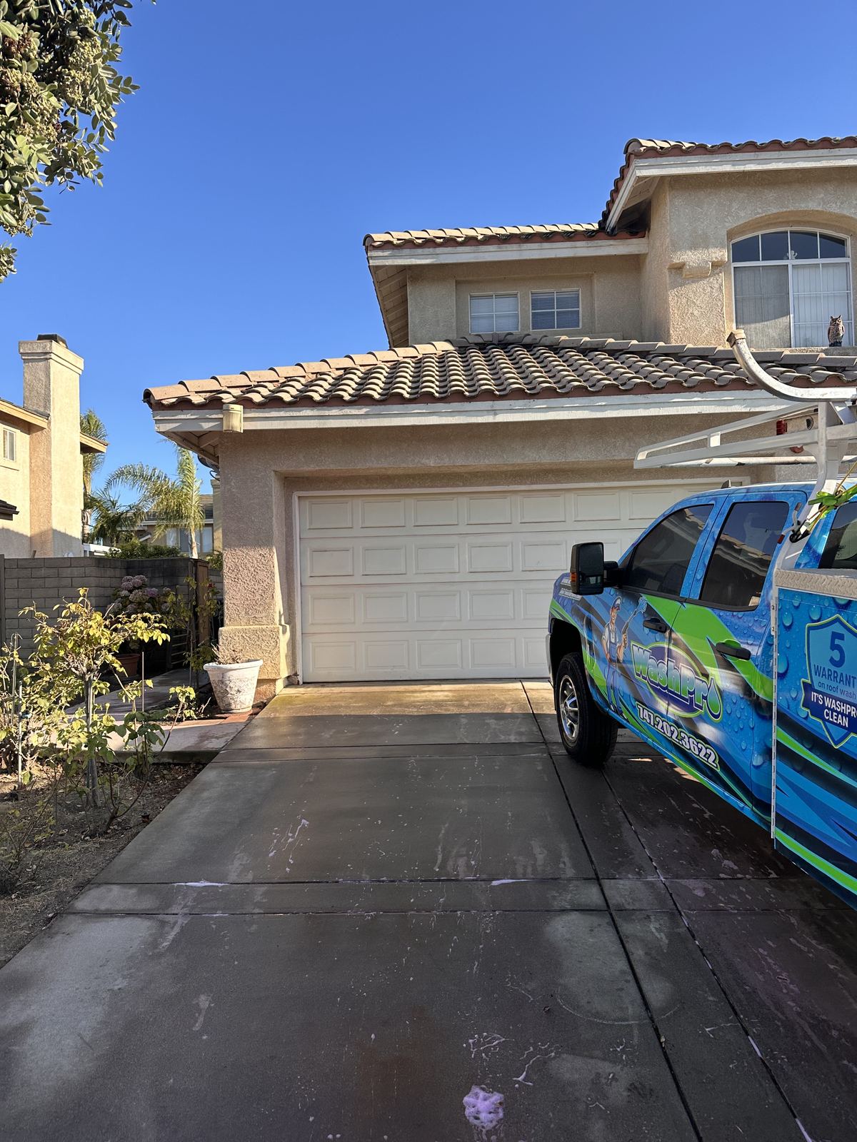 Valley Wash Pros truck in the driveway of a two-story tile roof home in the Central Valley, on site for a soft wash roof cleaning
