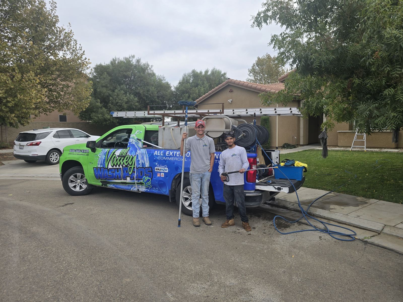 Valley Wash Pros window cleaning technicians with water-fed poles at the service truck in Fresno