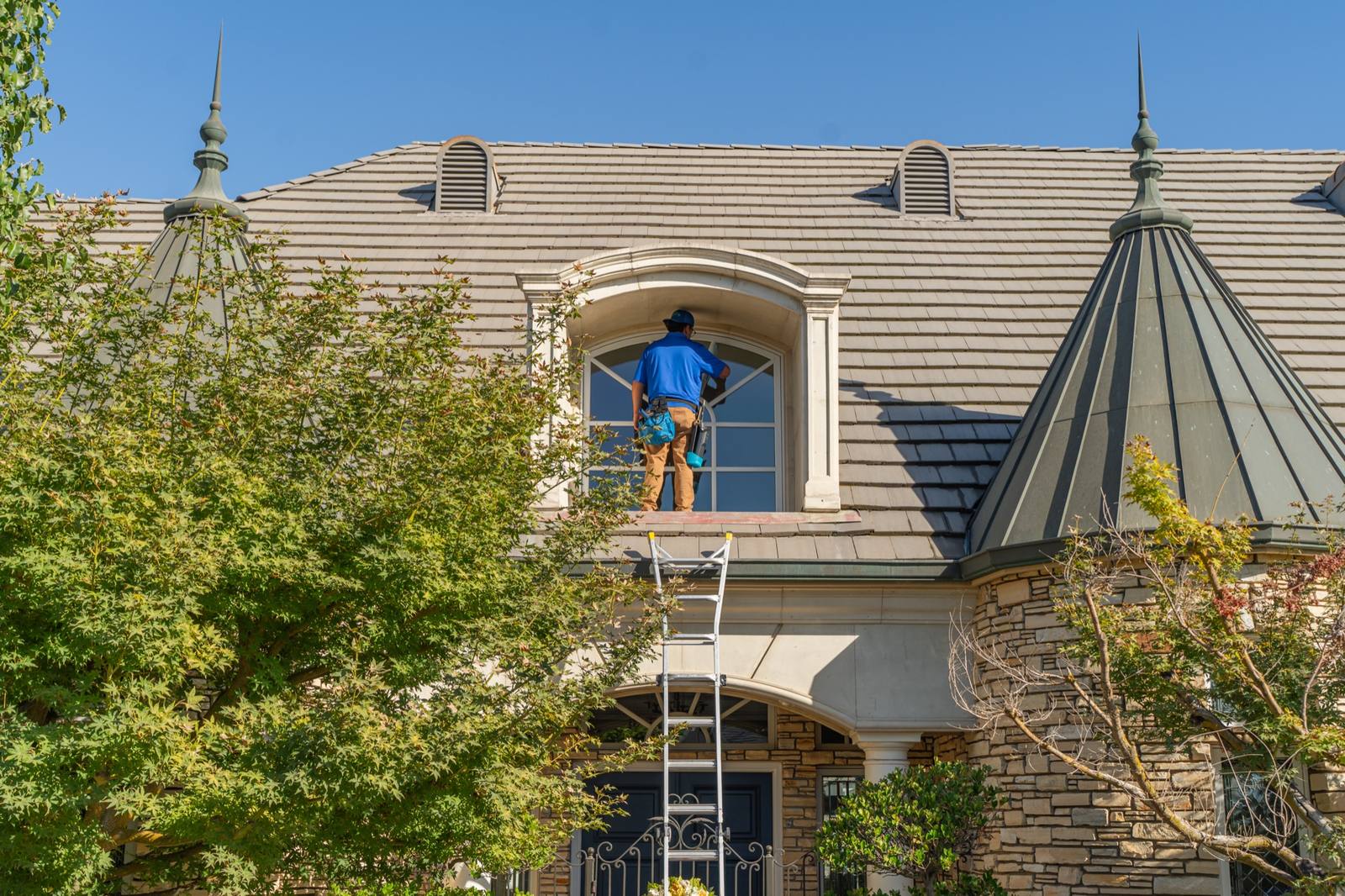 Valley Wash Pros technician cleaning a large second-story window on a Fresno estate